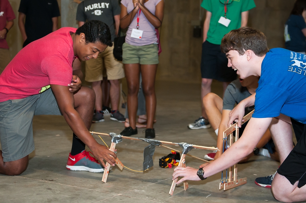 Two students holding a small catapult that was built during a summer camp