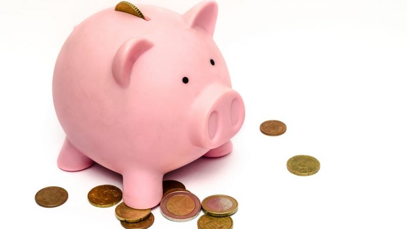 A piggy bank with pennies scattered around it.