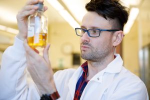 Dr. Lukasz Ciesla looks at a plant extract in a jar.