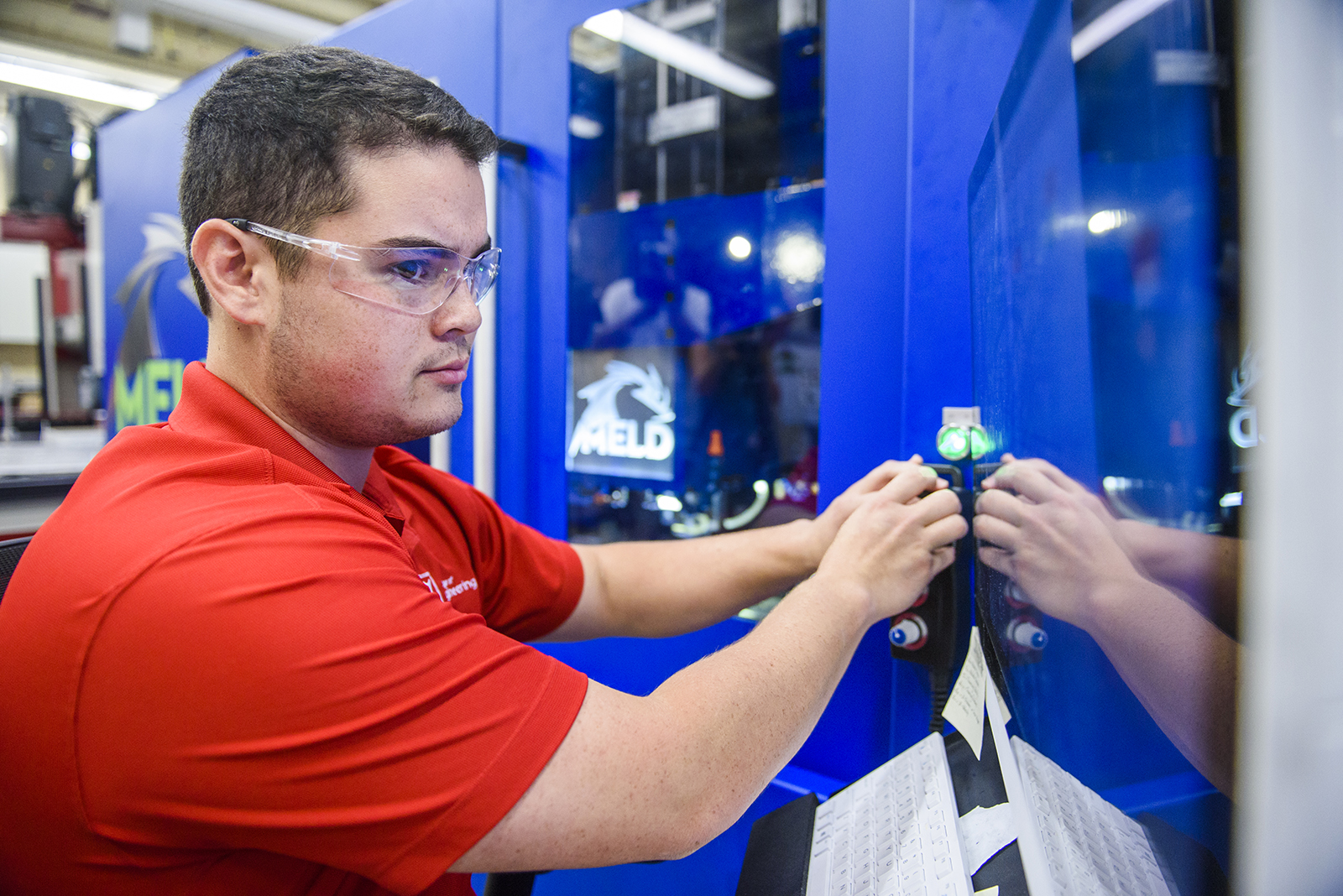 A student works the controls of a metal, 3D printer.