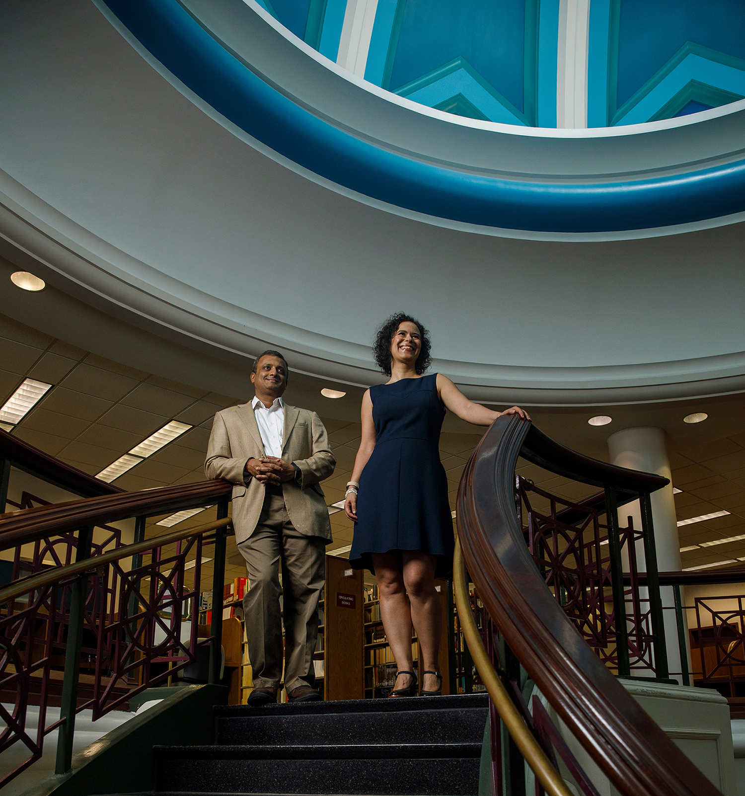 Business professors stand atop spiral staircase.