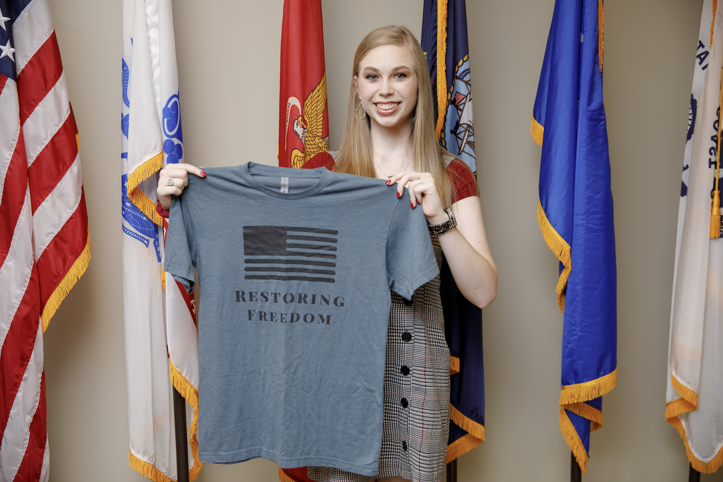 A female college student holds a T-shirt related to her non-profit organization