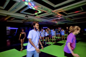 University students roller skate in a room of black lights and neon colors