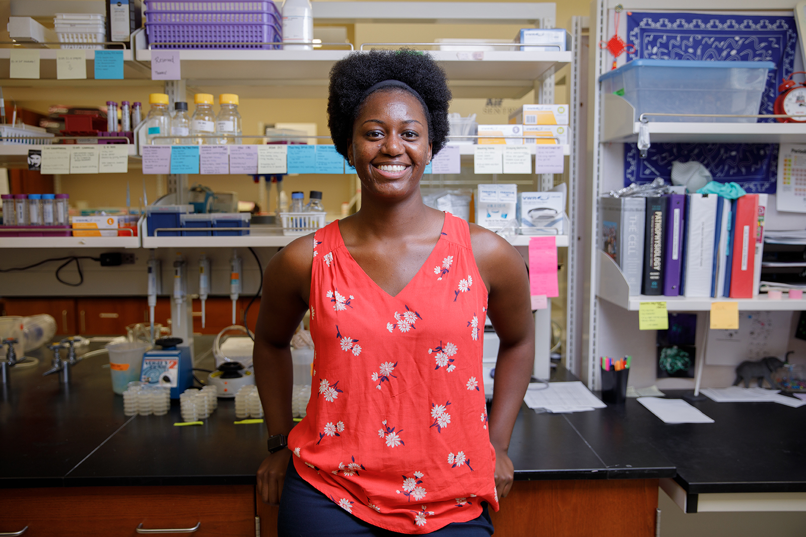A University of Alabama graduate student poses near her workspace in a biolgoical research lab.