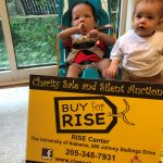 Two young children with signage promoting the RISE fundraiser.