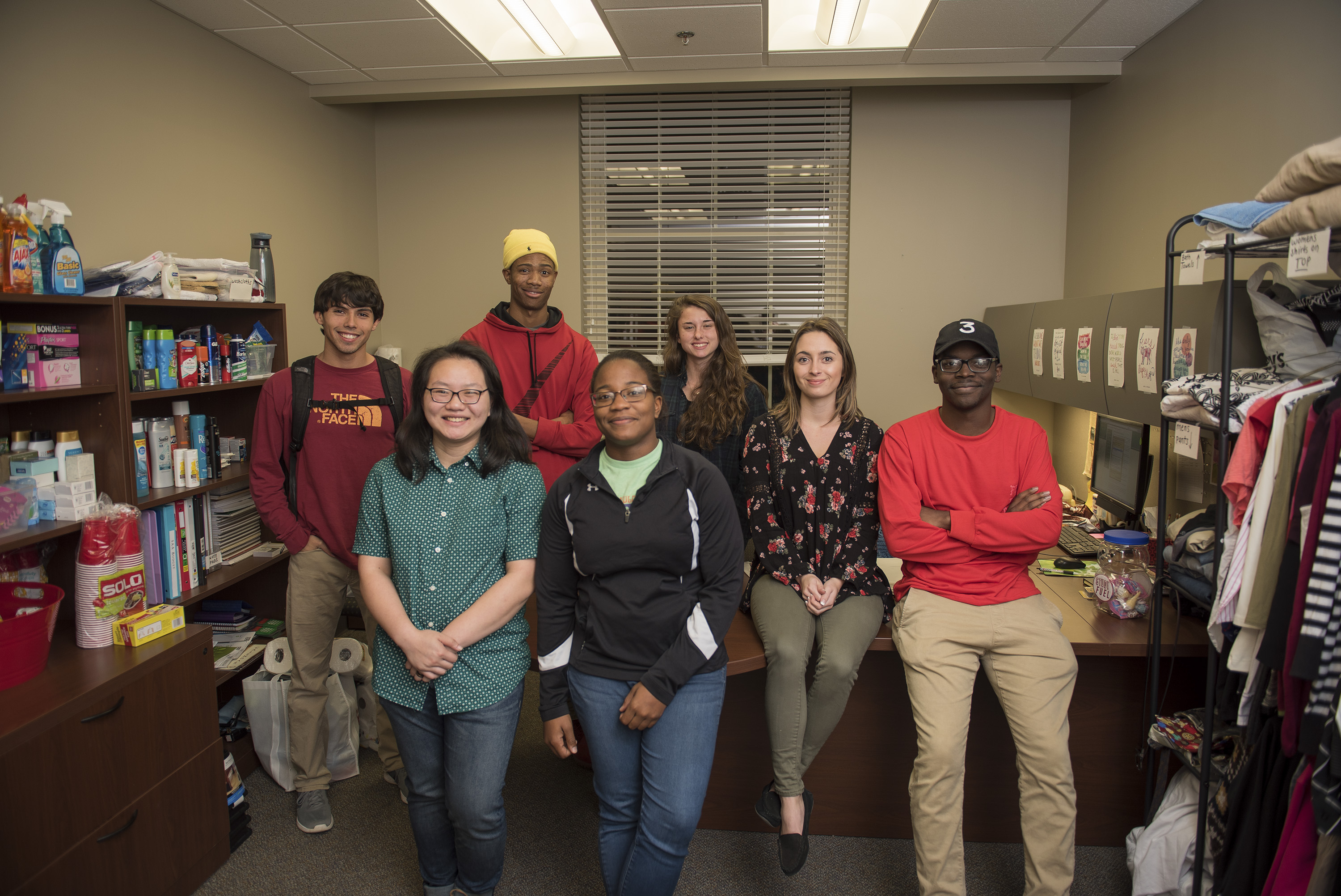 University students pose for a picture in an office filled with independent living supplies
