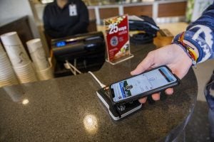  Person som använder mobiltelefon för att demonstrera ACT-kort i Apple Wallet