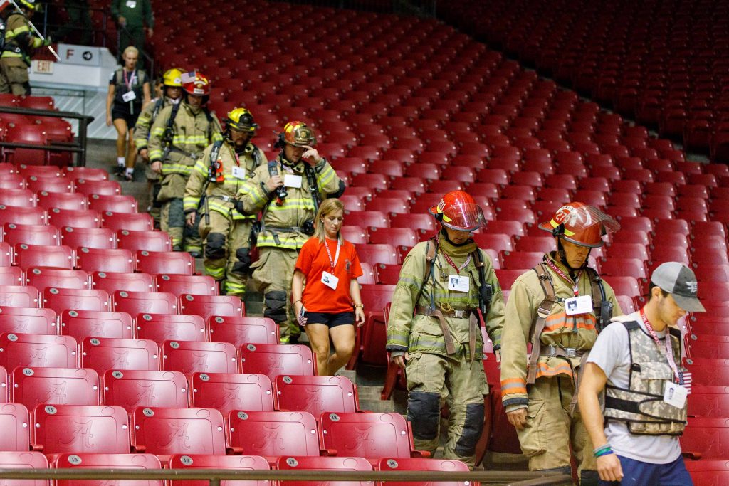 A line of fire fighters walks down the stairs at Coleman Coliseum