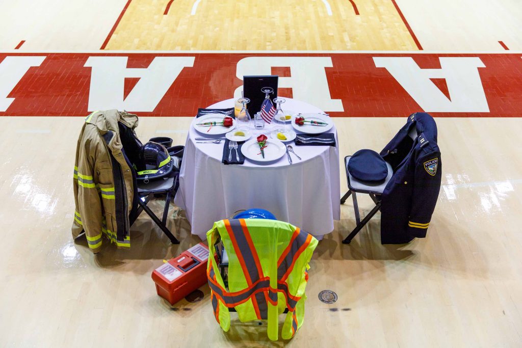 A small table with three chairs surrounding it. The chairs have a firefighter, police and EMT uniform on them symbolizing first responders who died on 9/11.