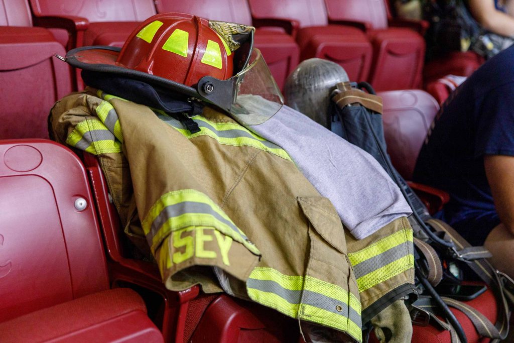 A firefighter's helmet and jacket lay on an empty chair