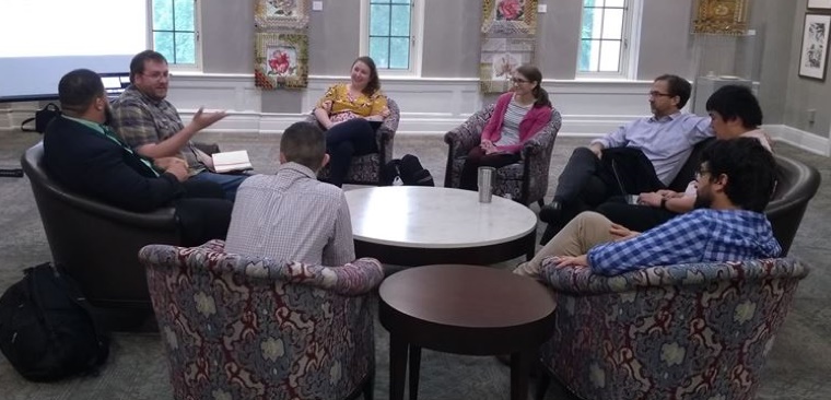 Members of the University of Alabama and Auburn University talk around a table