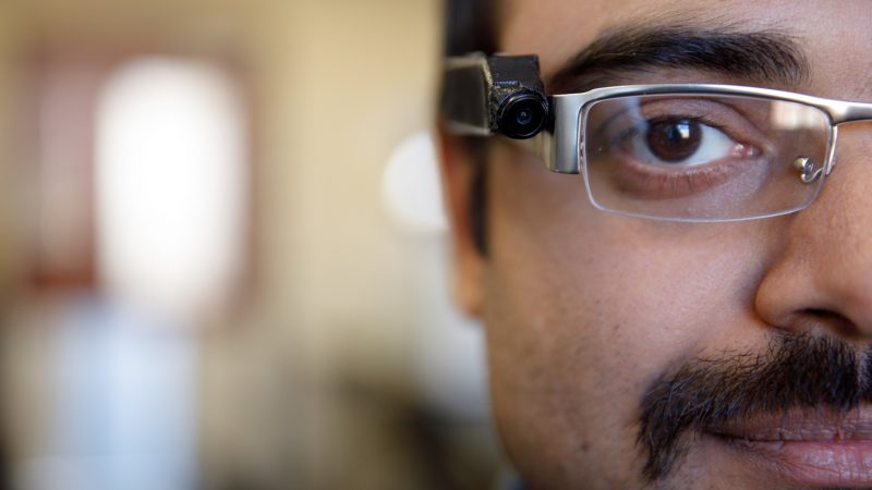 A close-up of a UA doctoral student wearing glasses with the ingestion monitor attached.