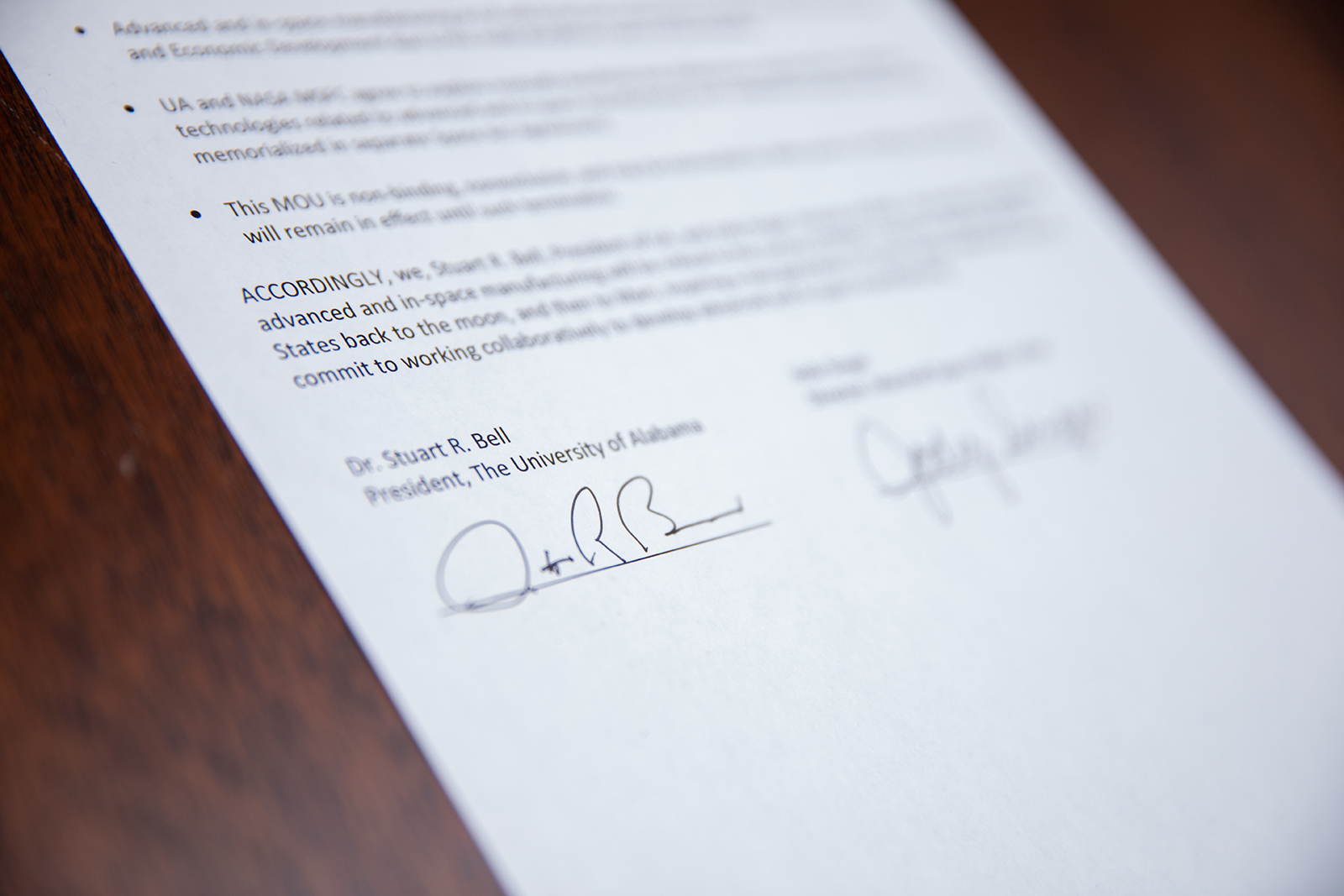 A signed agreement on paper between NASA and The University of Alabama rests on a conference table.