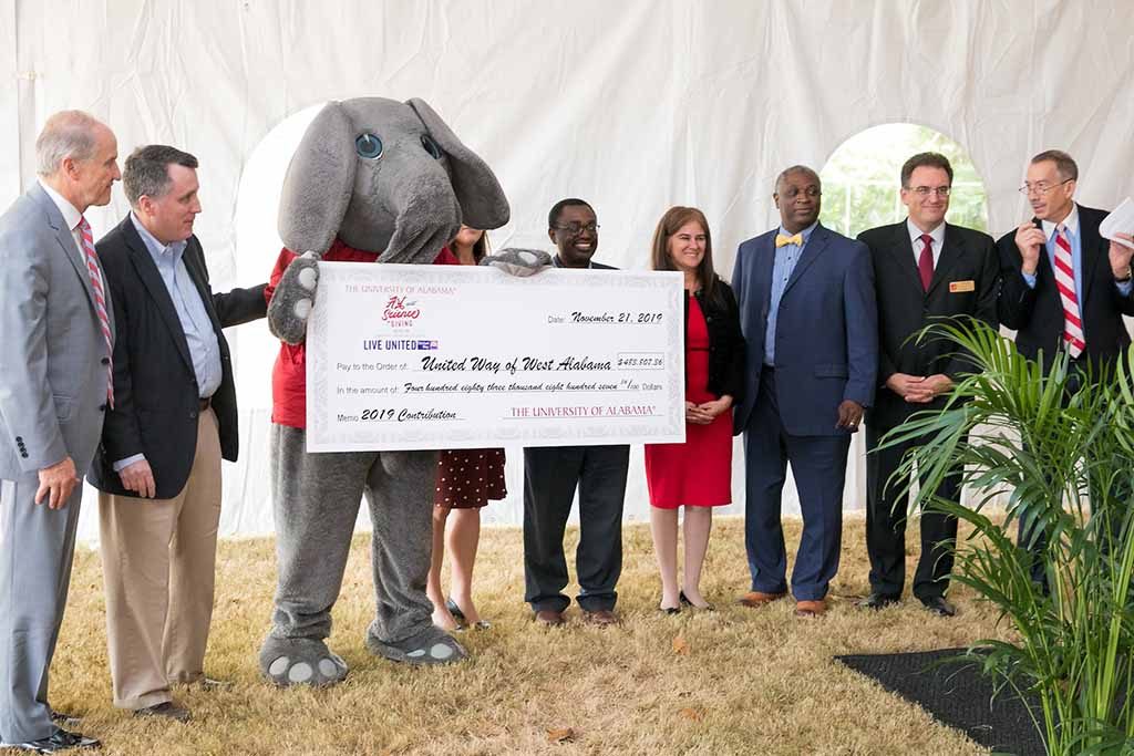 Big Al holding large check surrounded by people