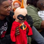 Father holds baby wearing a costume from the movie The Incredibles