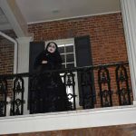 Woman dressed as ghost on upper porch of the Gorgas House