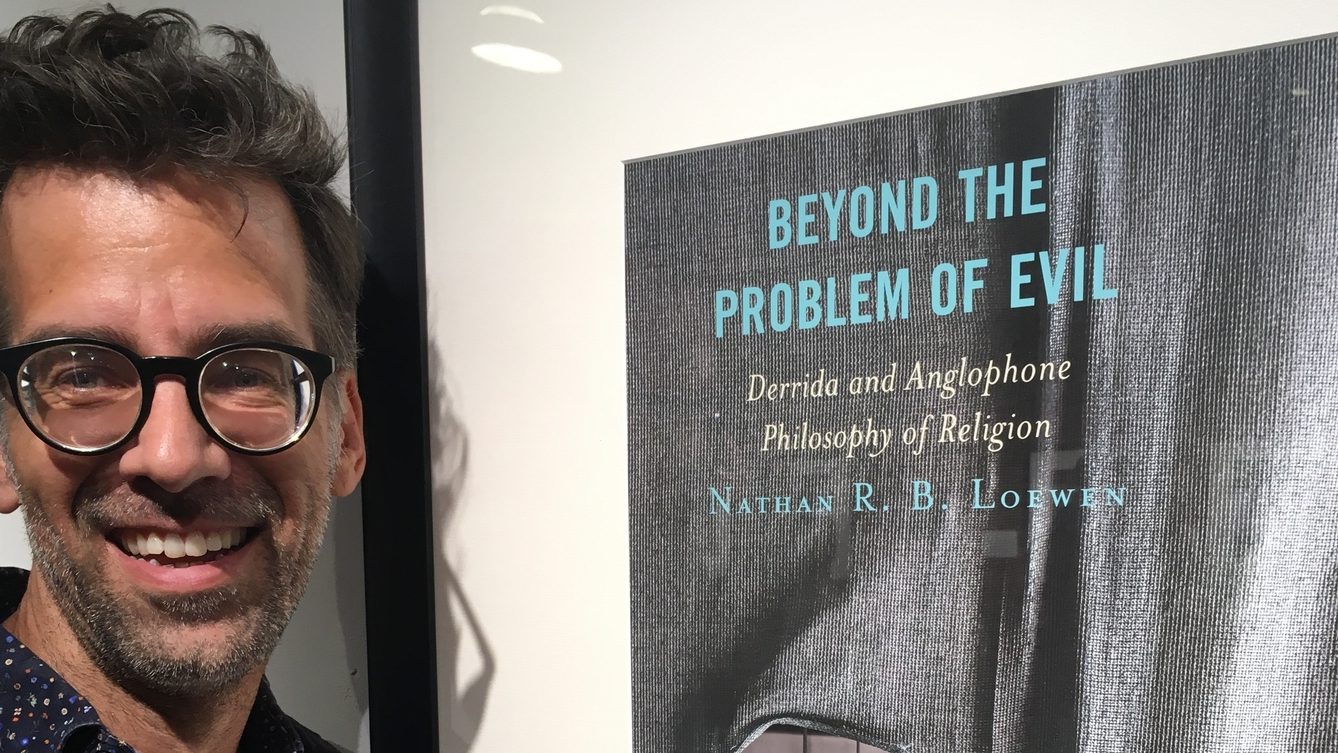 Dr. Nathan Loewen beside a photo of his book.