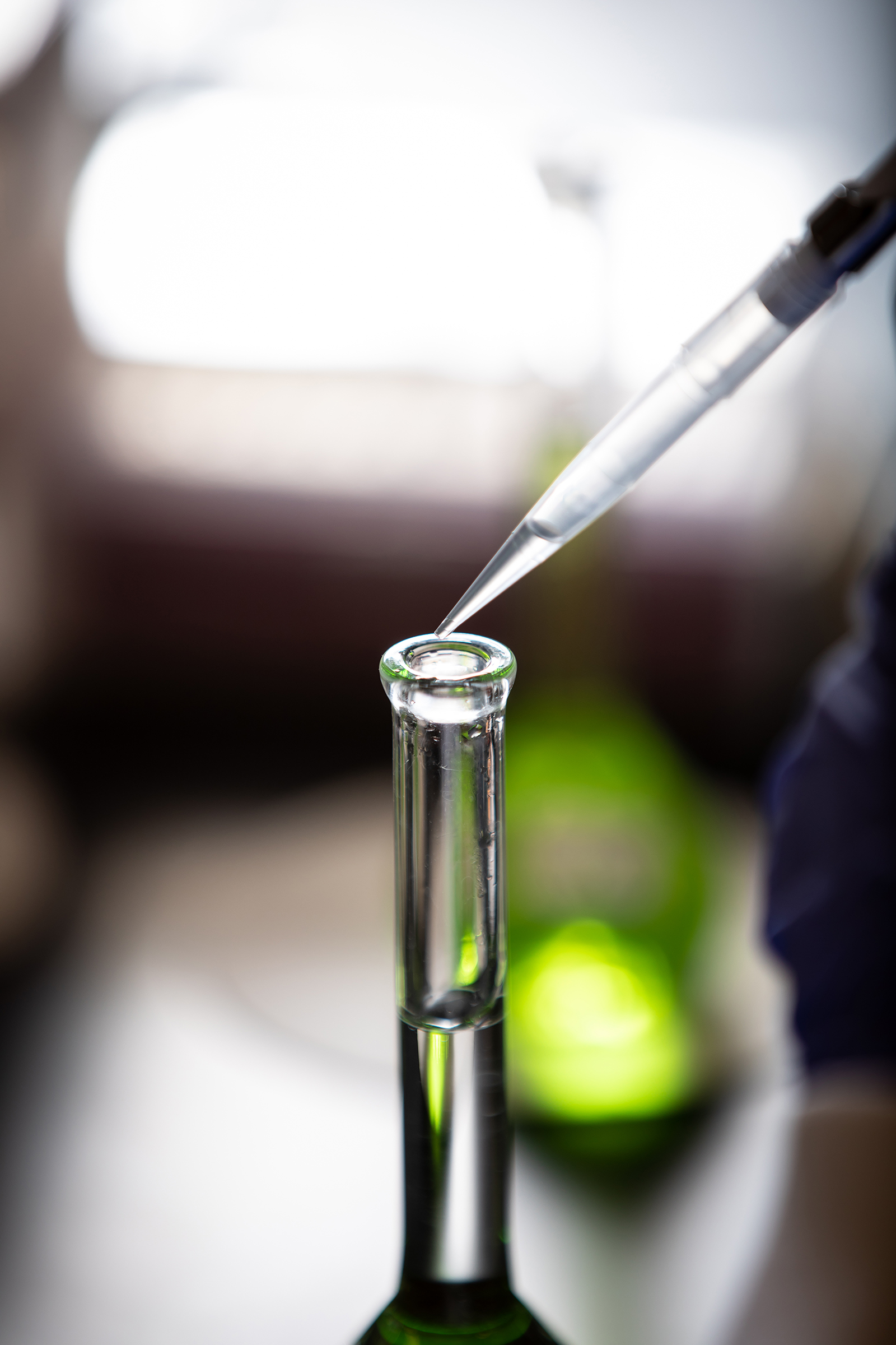 A liquid is dropped into a beaker in a lab.