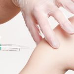 Posed photo of hands injecting a syringe into an arm.