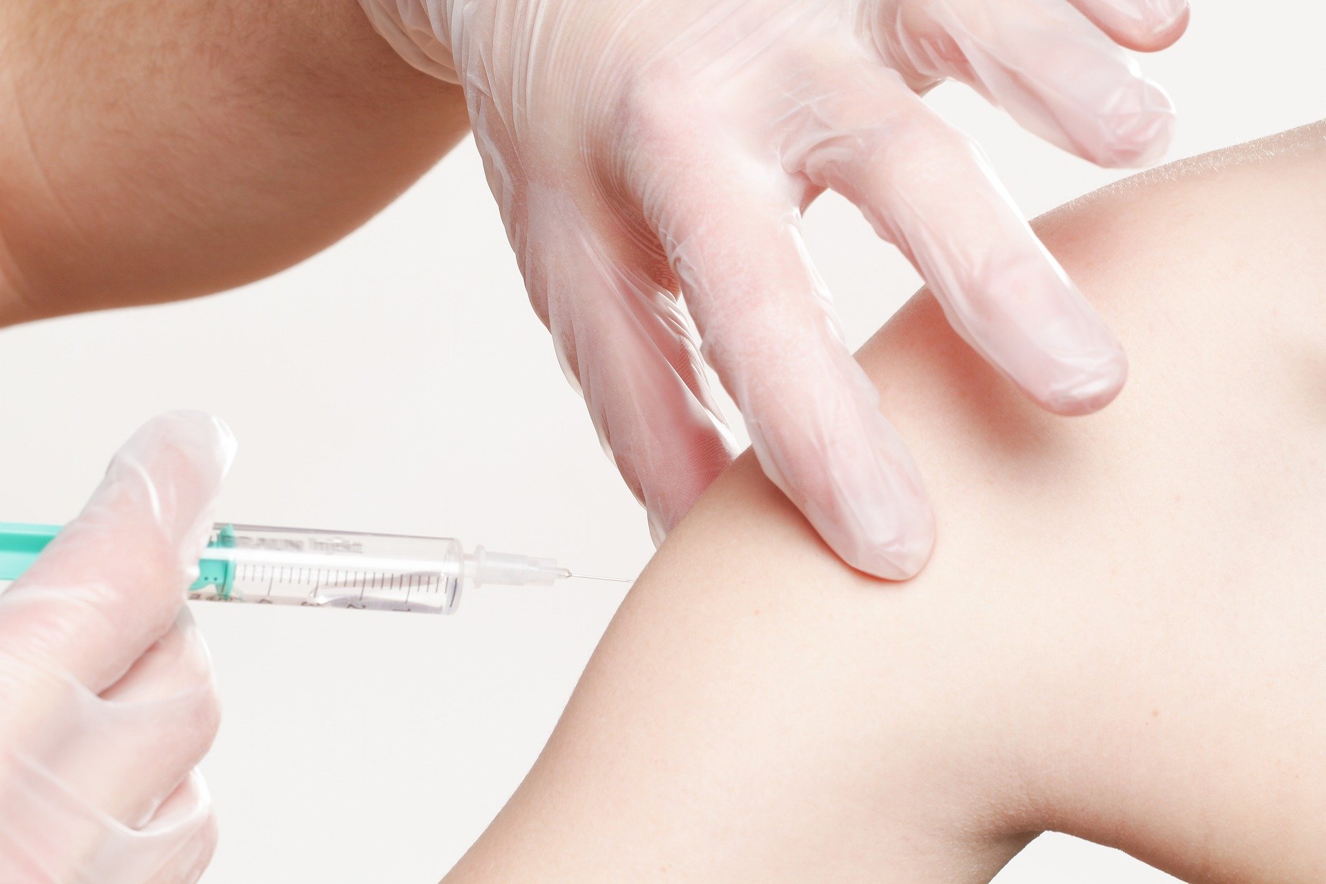 Posed photo of hands injecting a syringe into an arm.