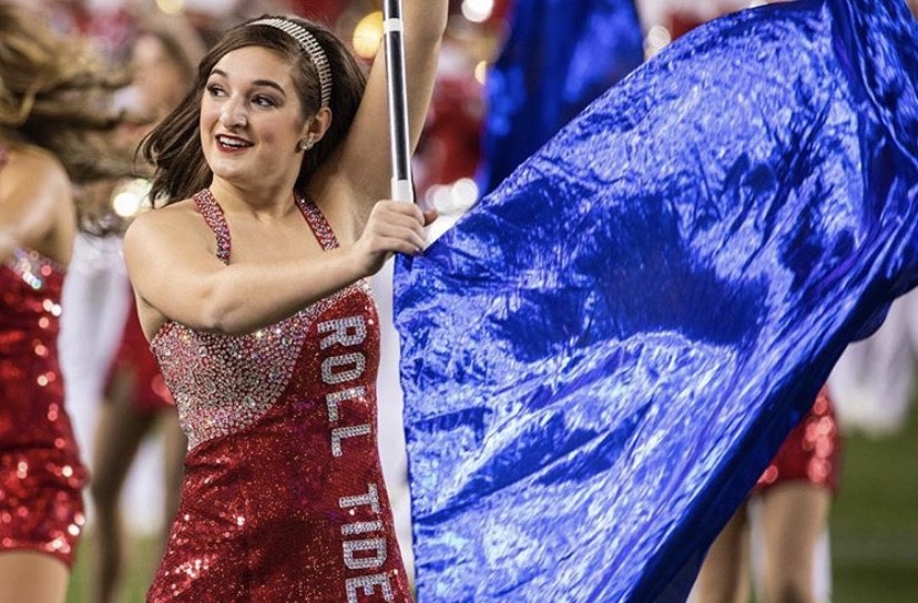Female Colorguard member performs on field with flag in hand.