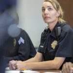 A female police officer listens to a teacher in a classroom