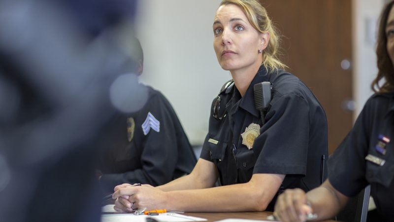 A female police officer listens to a teacher in a classroom