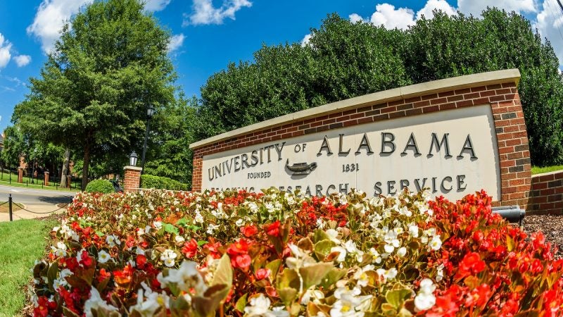 The University of Alabama entrance marker is pictured with flowers in front.