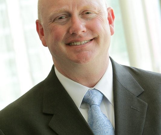 A man in a suit smiles at the camera.