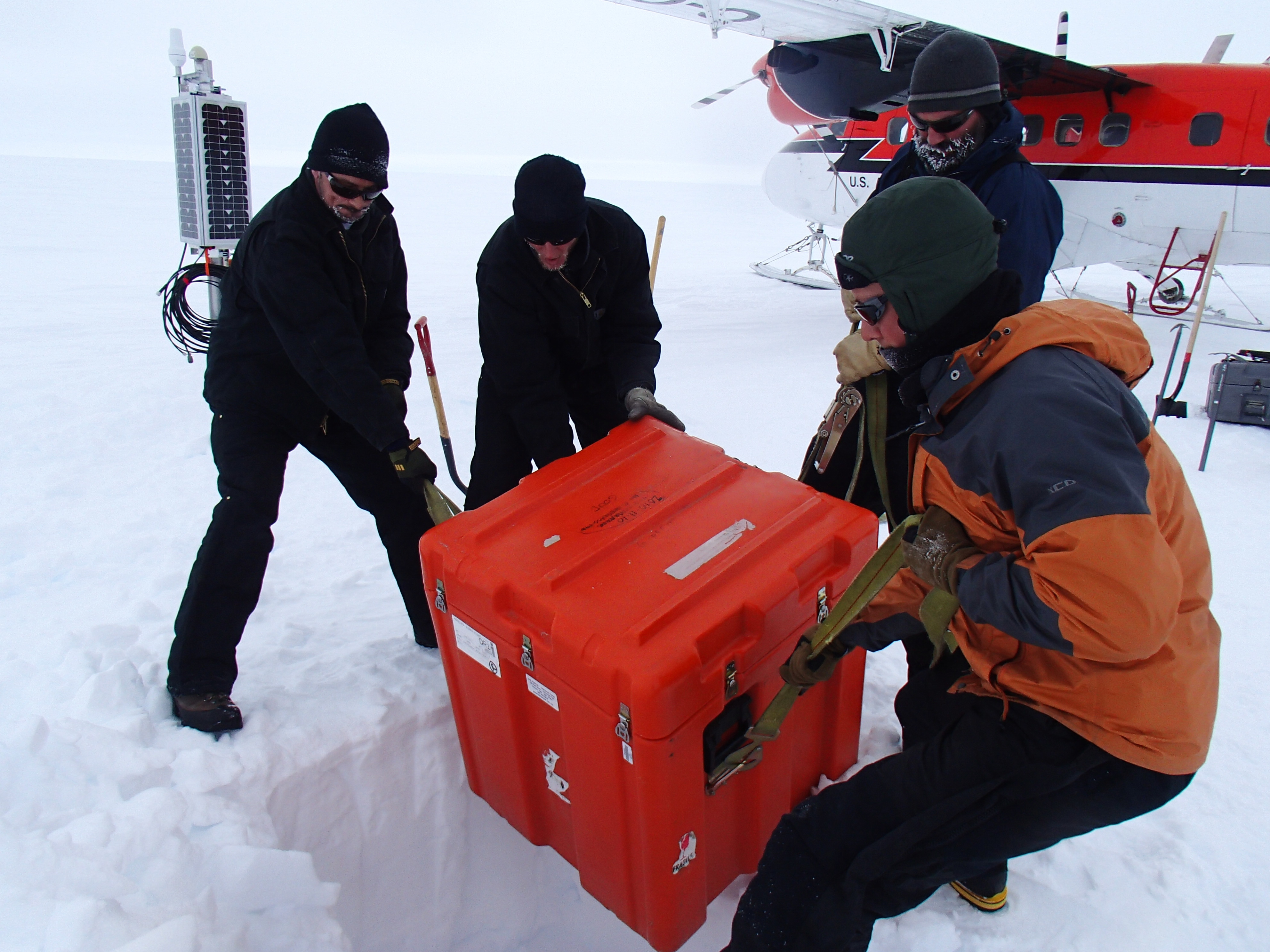 Four researchers handling equipment in the snow