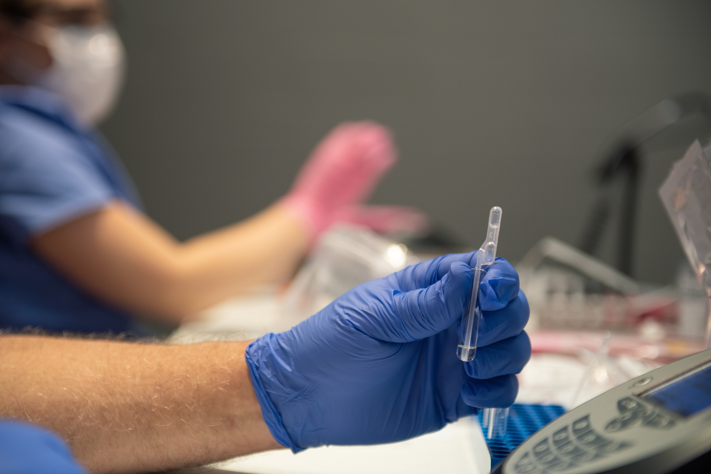 A testing sample is handled by a gloved hand