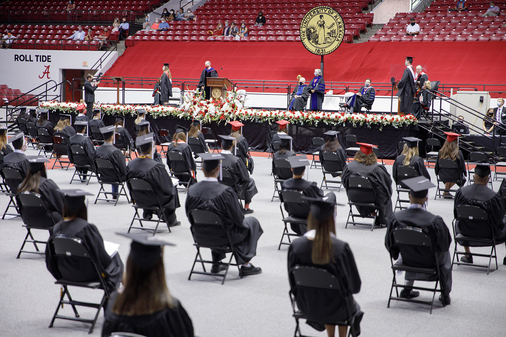 Students sit in cap and gown at commencement ceremony.