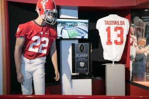 A display inside the Bryant Museum features a manikin wearing a University of Alabama football uniform, a trophy from the College Football Playoff and Tua Tagovailoa's jersey.