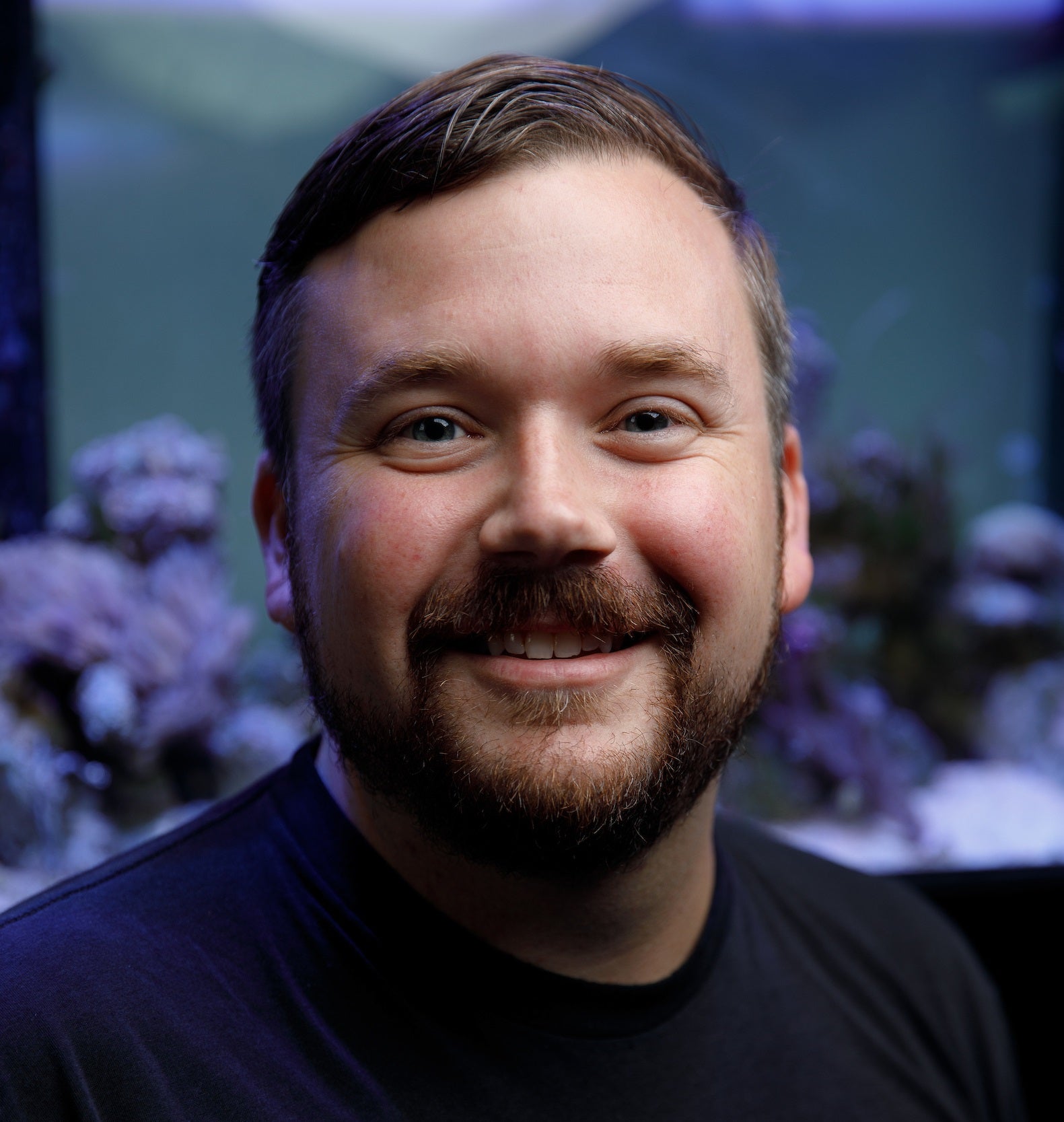 A portrait of a man in front of an aquarium.