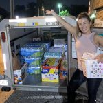 Lady stands in front of U-Haul full of supplies.