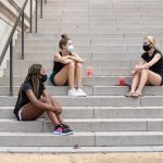 three female students sit on the steps of Gorgas Library talking