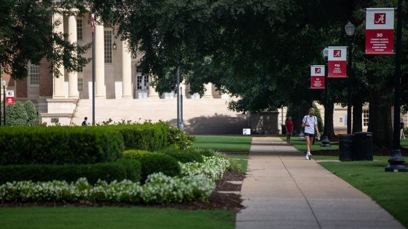 Students with masks walk on teh Quad in front of Gorgas Library.
