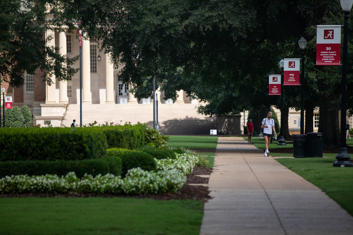 Students with masks walk on teh Quad in front of Gorgas Library.