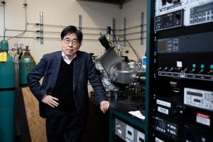 A man stands in an electrical engineering lab for a portrait.