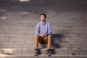 A man sits on concrete stairs for a portrait.