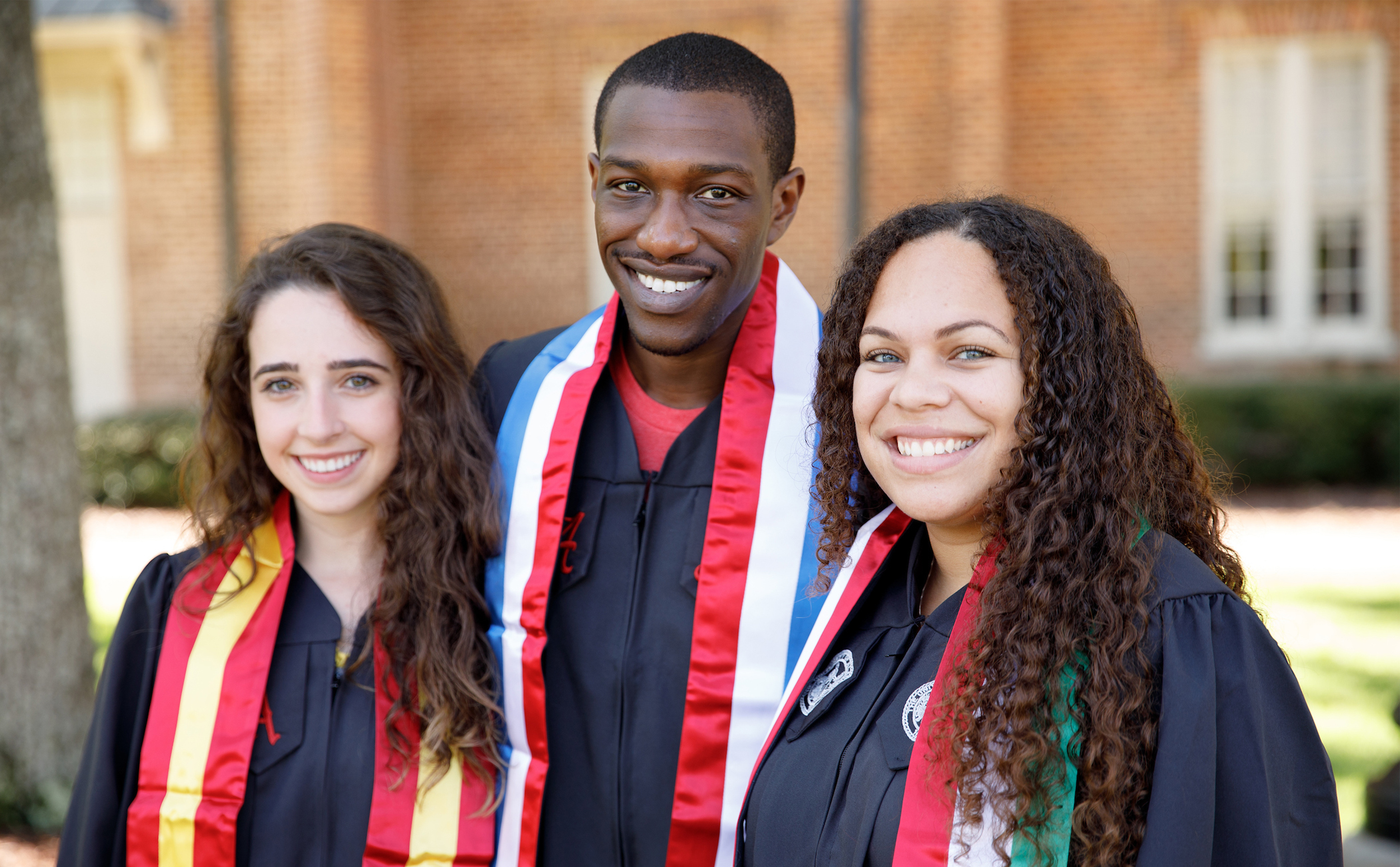 Three students wearing graduation gowns.