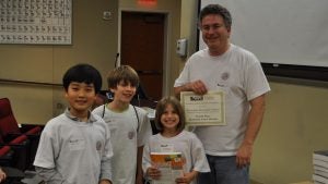 Three elementary students pose with Dr. Jeff Gray at the first UA robotics competition in 2011.