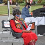 A woman sits in a chair reading a Veterans Day Ceremony program.