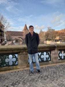 A man poses in front a castle in Europe.