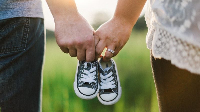 Couple holding hands with baby shoes
