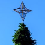 Large silver star on top of outdoor tree