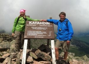 A man and woman stand in front of a Mount Katahdin sign.
