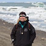 Leigh Mayberry stands in front of an icy Arctic Ocean.