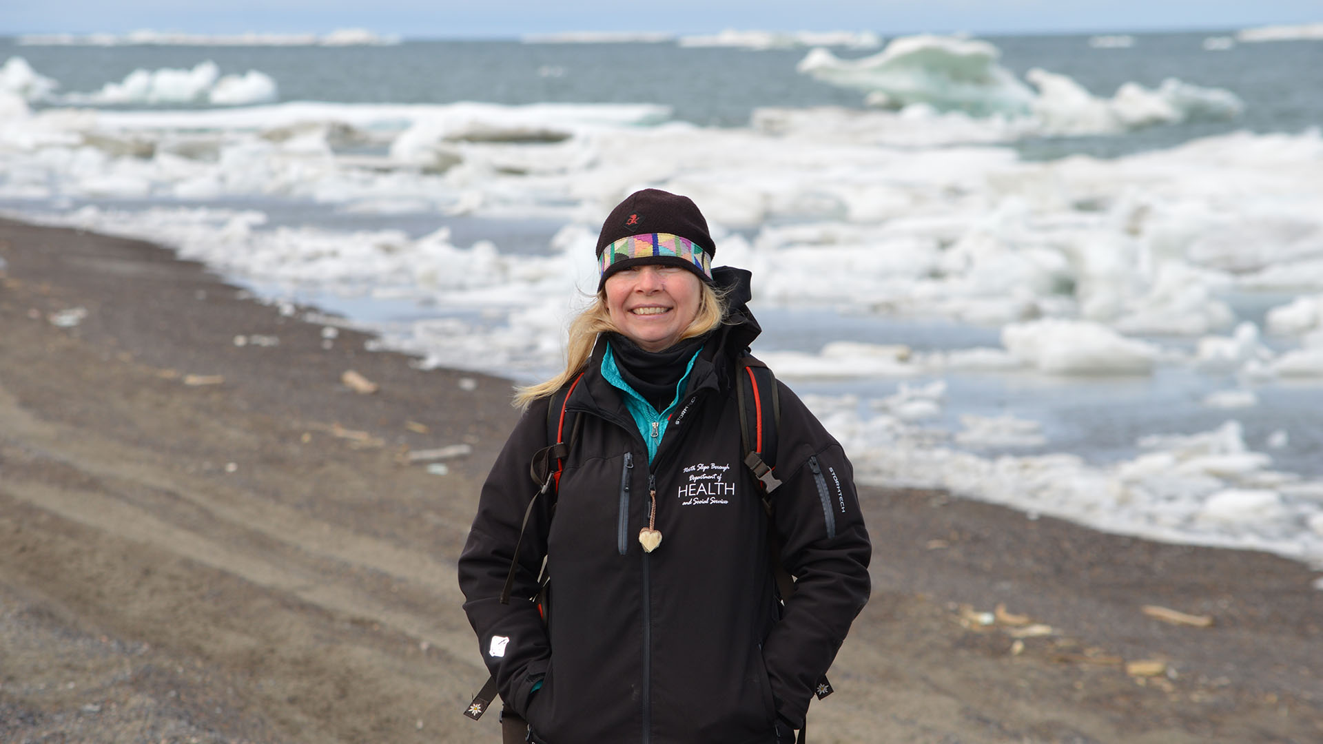 Leigh Mayberry stands in front of an icy Arctic Ocean.