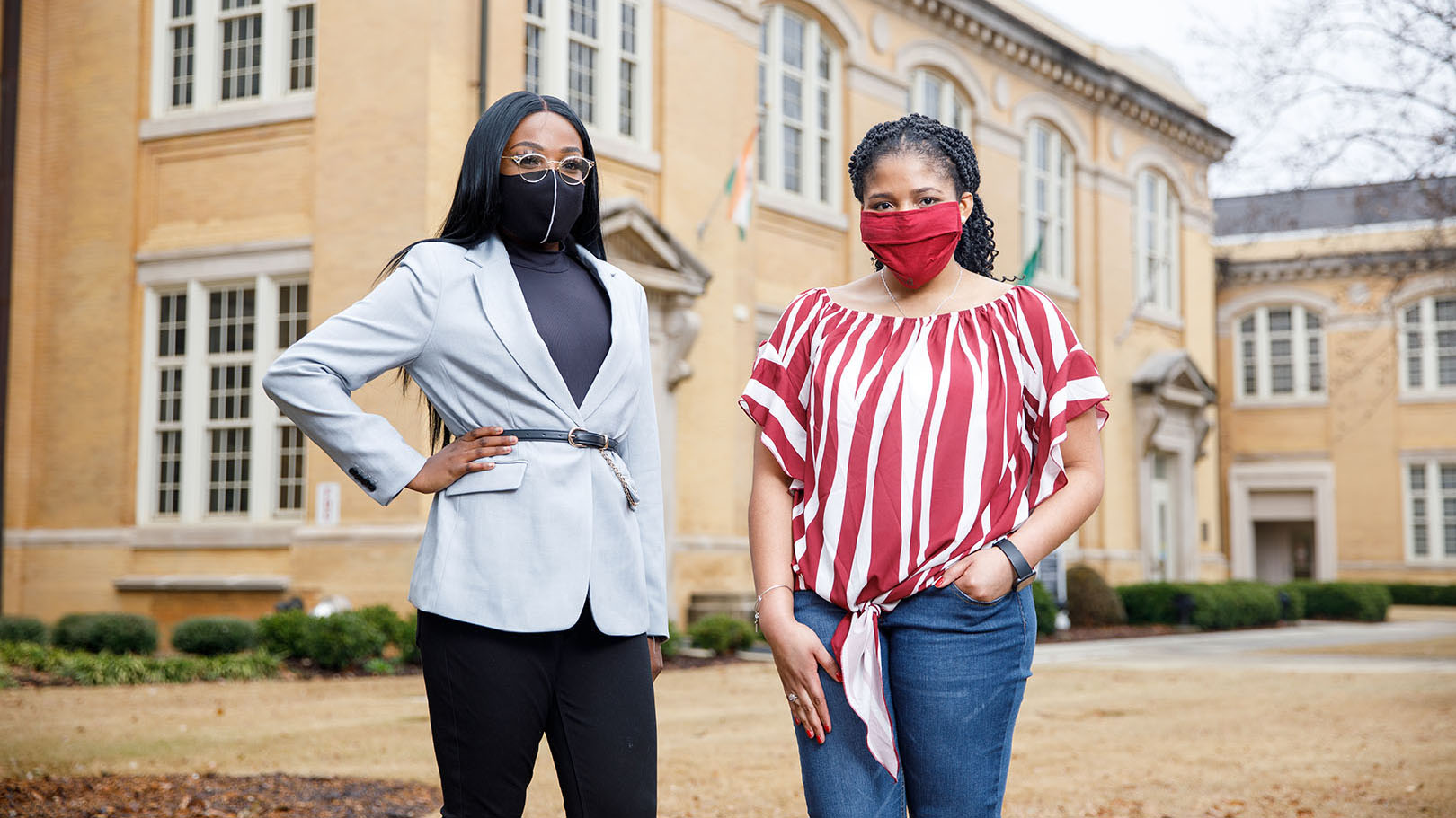 Two UA students in masks stand in front of B.B. Comer Hall.